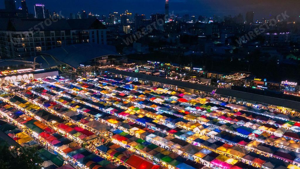 An aerial shot of colorful market tents with lit lights at night time