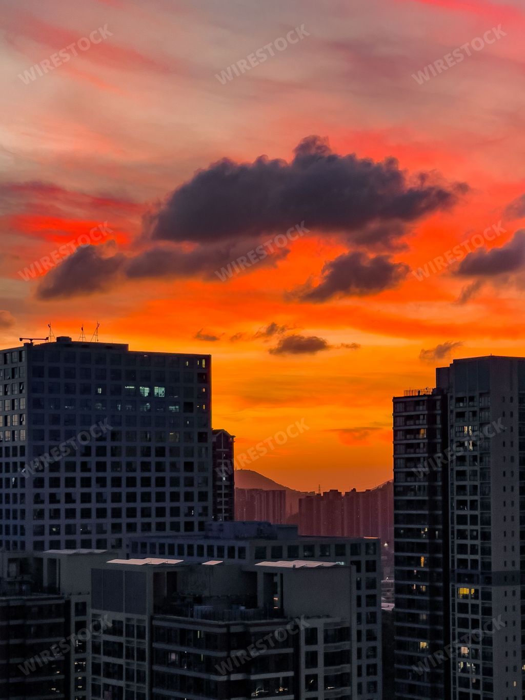A vertical shot of city buildings against the background of the orange sky at sunset.