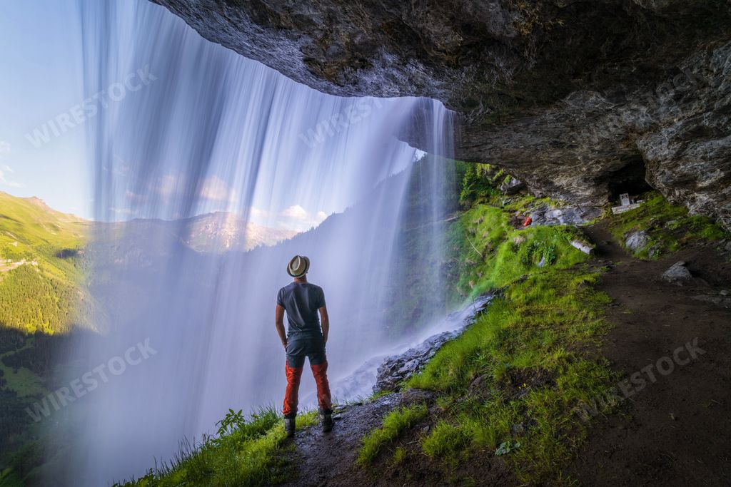 A man standing on the cliff admiring the waterfall in Austria