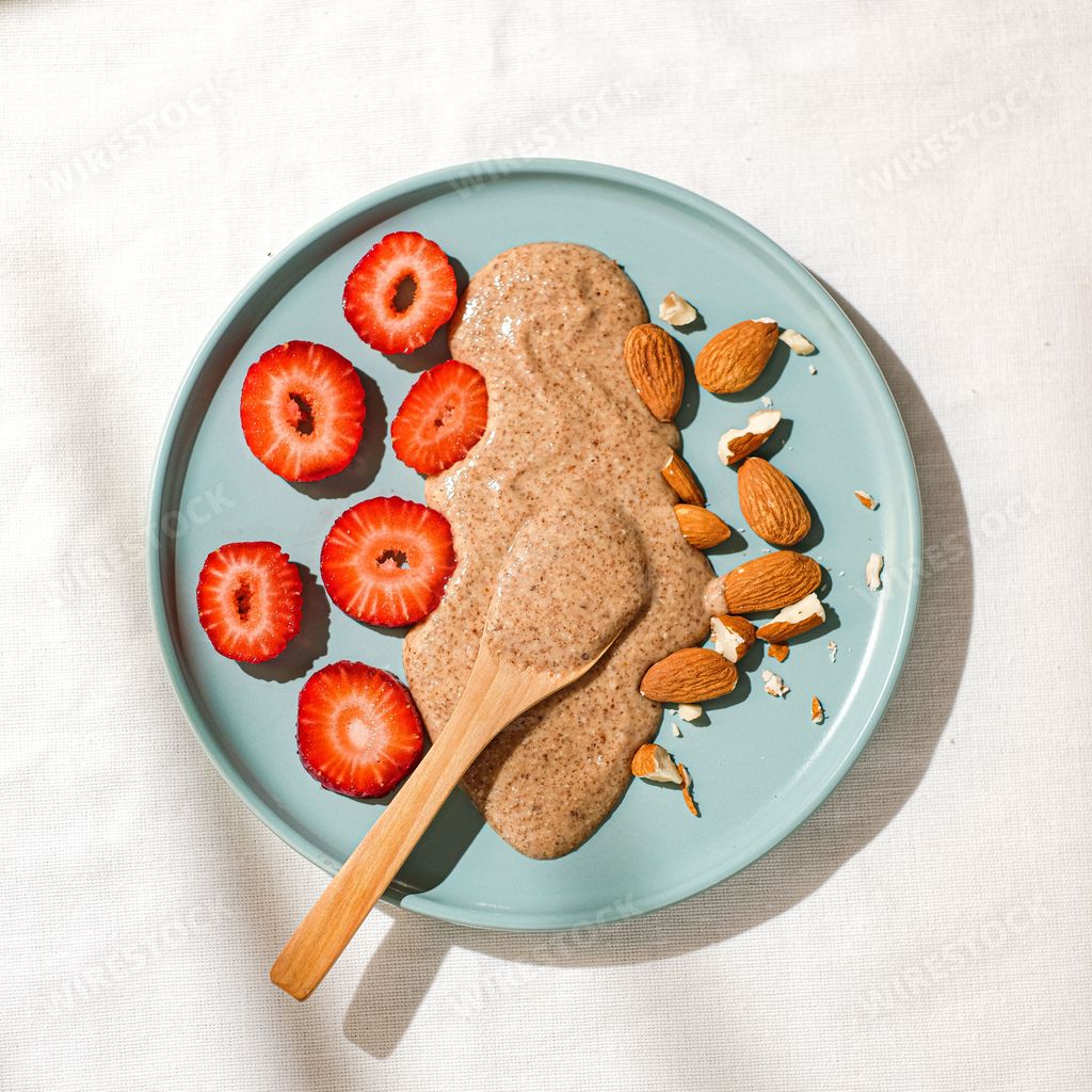 The top view of an almond butter strawberries and almonds in the blue plate