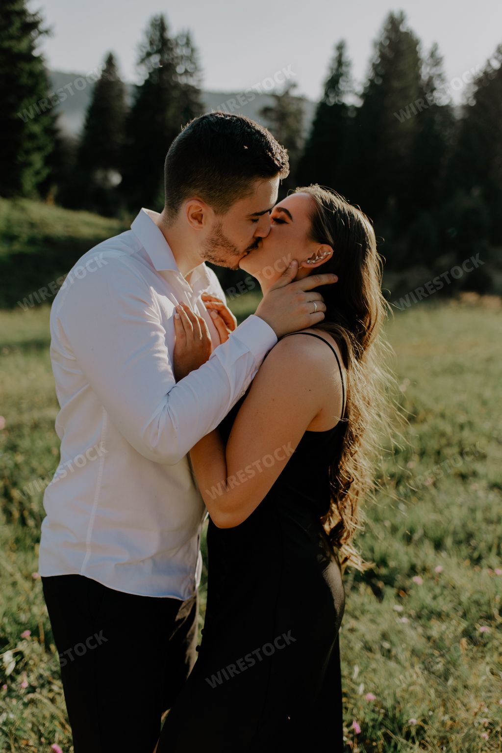 A vertical shot of a young romantic couple kissing on a meadow