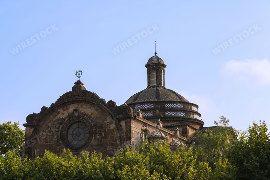 Horizontal photo of an old church sitting in a park in Barcelona, Spain, with a beautiful blue sky above