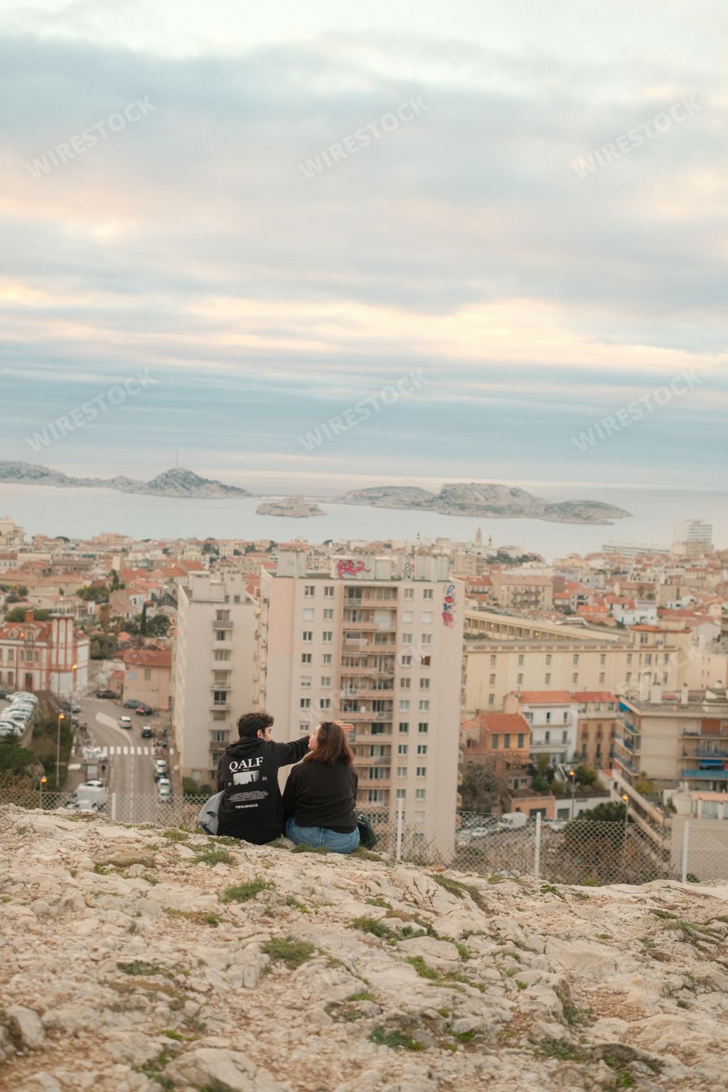 A romantic couple sitting on a cliff edge admiring cityscape from hilltop