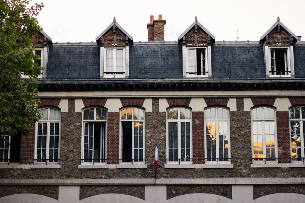 The view of a medieval fire station building with the French flag hanging from the facade in Paris