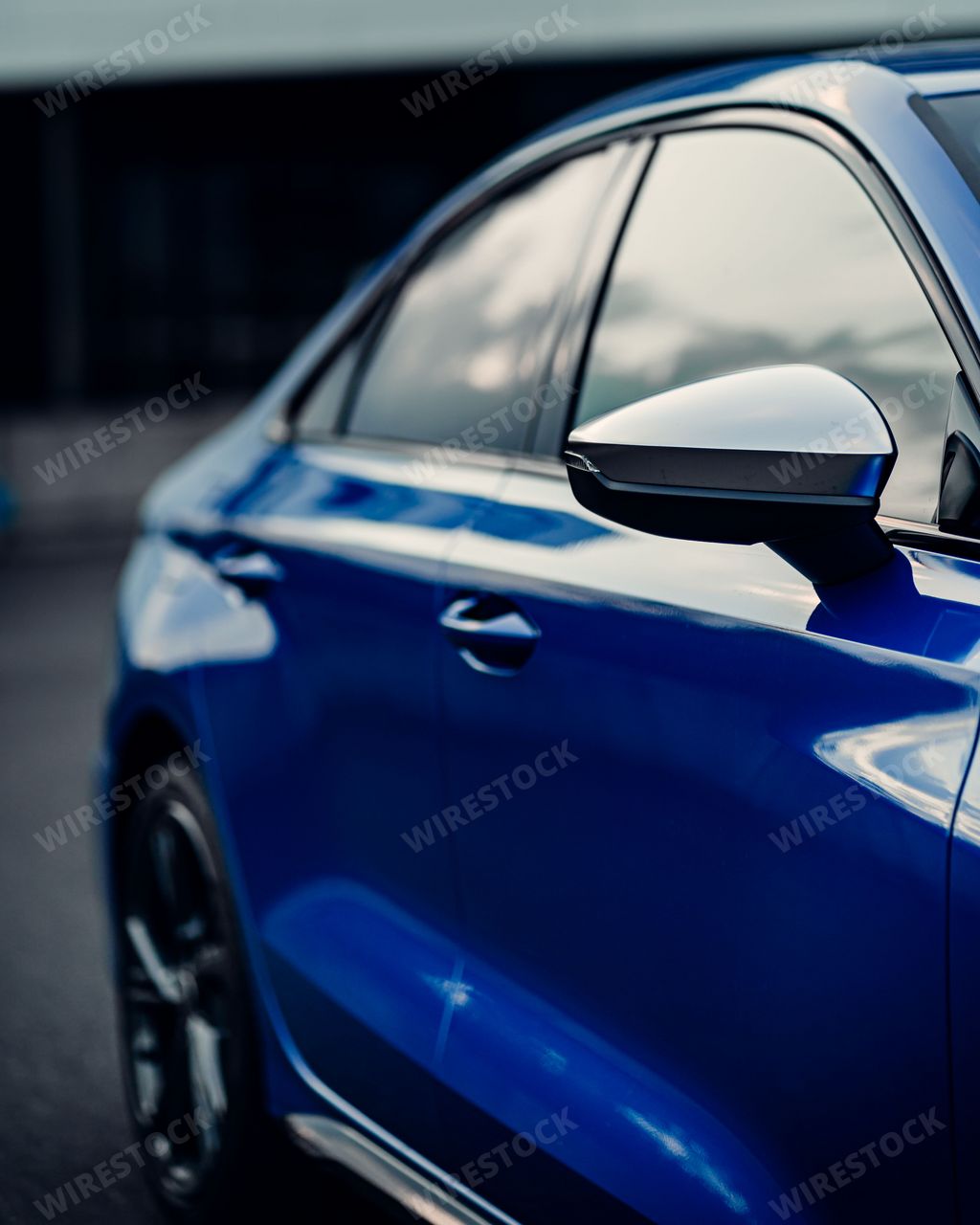 A side shot of a shiny blue sport car mirror and windows with blur background, vertical shot