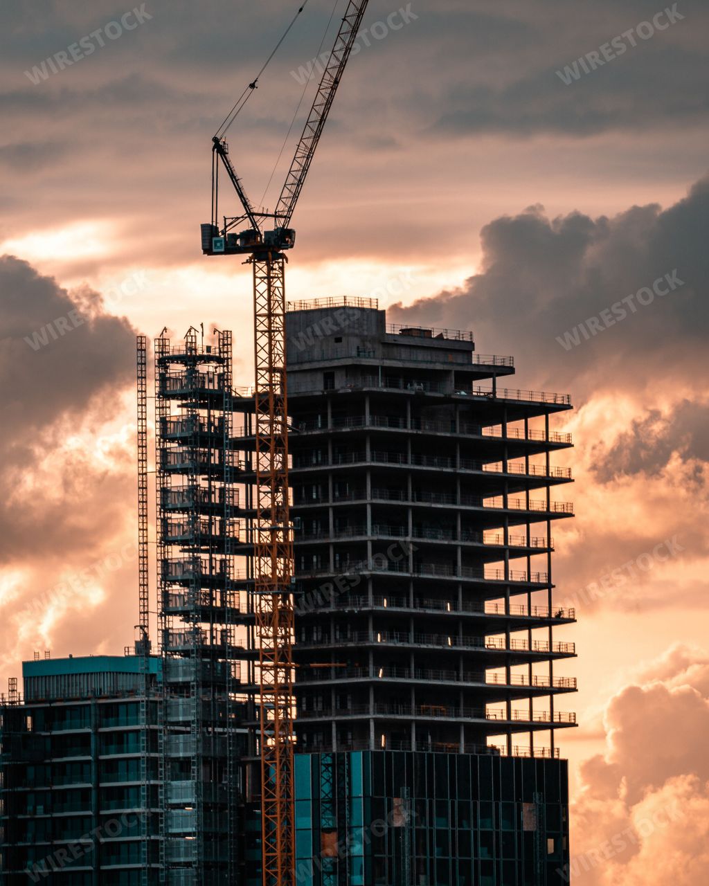 A vertical shot of a crane building a skyscraper during a sunset