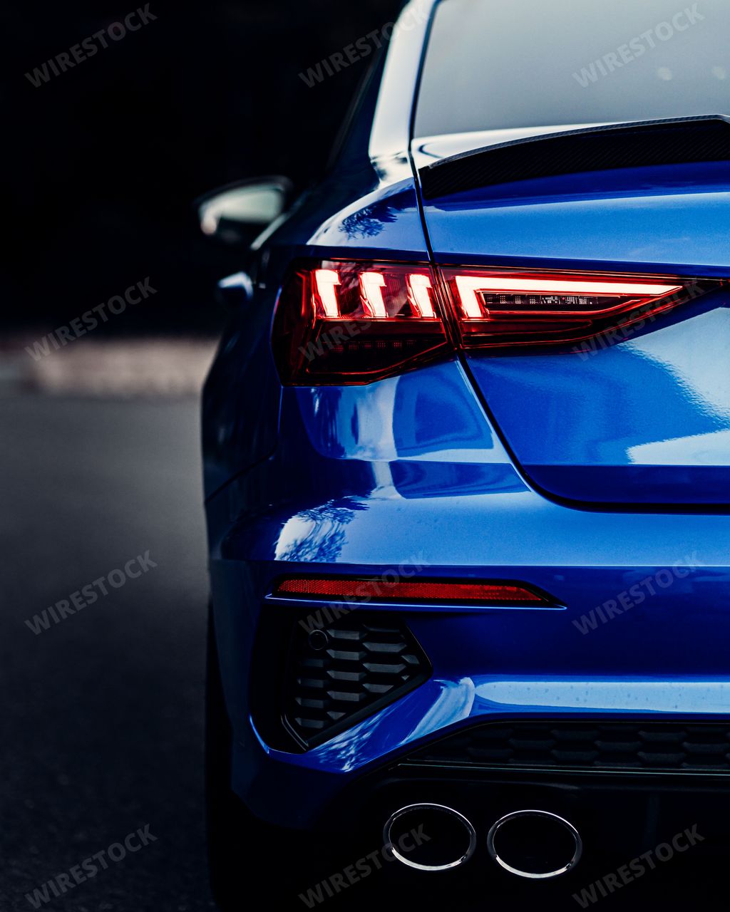 A back view of a shiny blue sport car lights with blur background, vertical shot