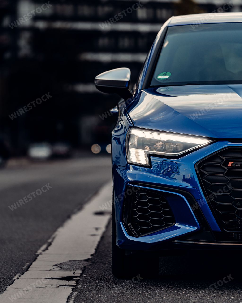A front view of a shiny blue sport car mirror with blur background, vertical shot
