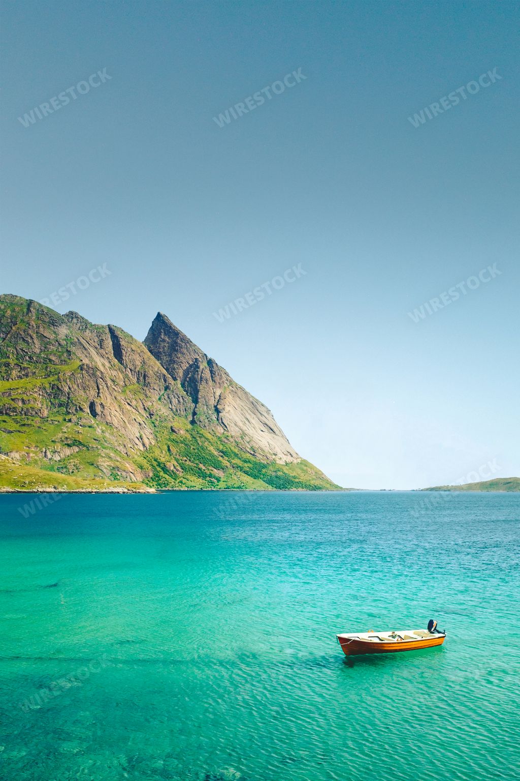 A vertical shot of a boat sailing on the sea surrounded by rocky cliffs in Norway