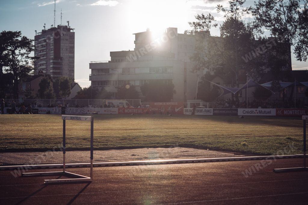 An empty running athleticism trail track and green field at sunset time