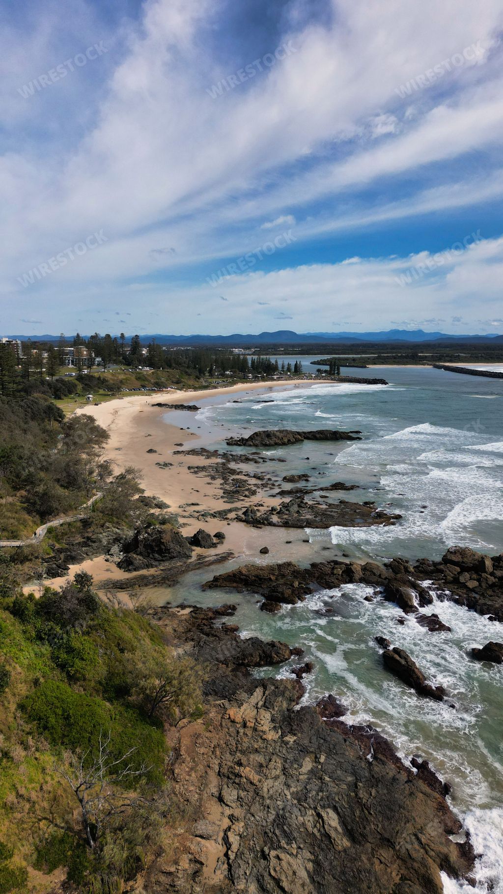 Scenic view of Town Beach in Port Macquarie, NSW, with green trees and buildings on sandy and rocky coast
