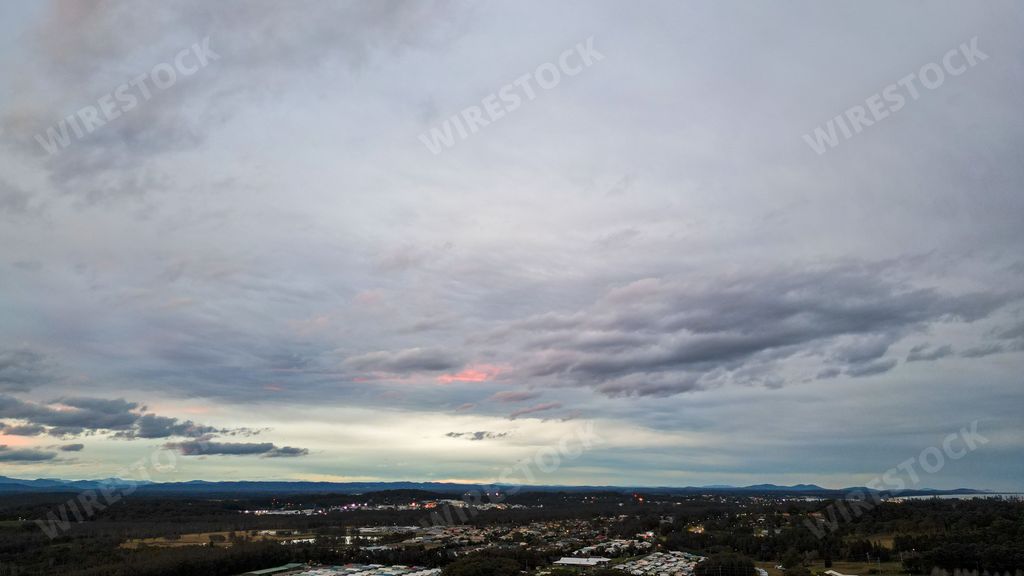An aerial shot of the Port Macquarie town with surrounding forest under the cloudy sky in Australia