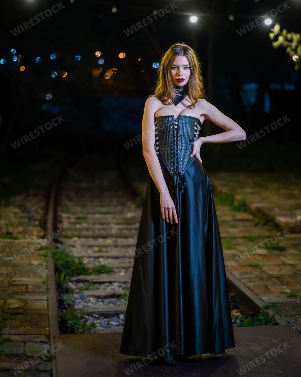 A portrait of a hot woman in a gothic costume posing outdoors at night
