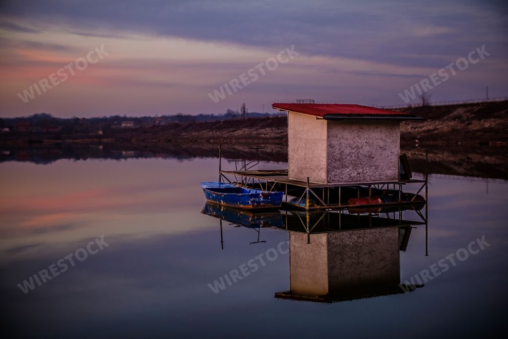 A scenic view of an old abandoned house in the Paljuvi lake at sunset in Serbia
