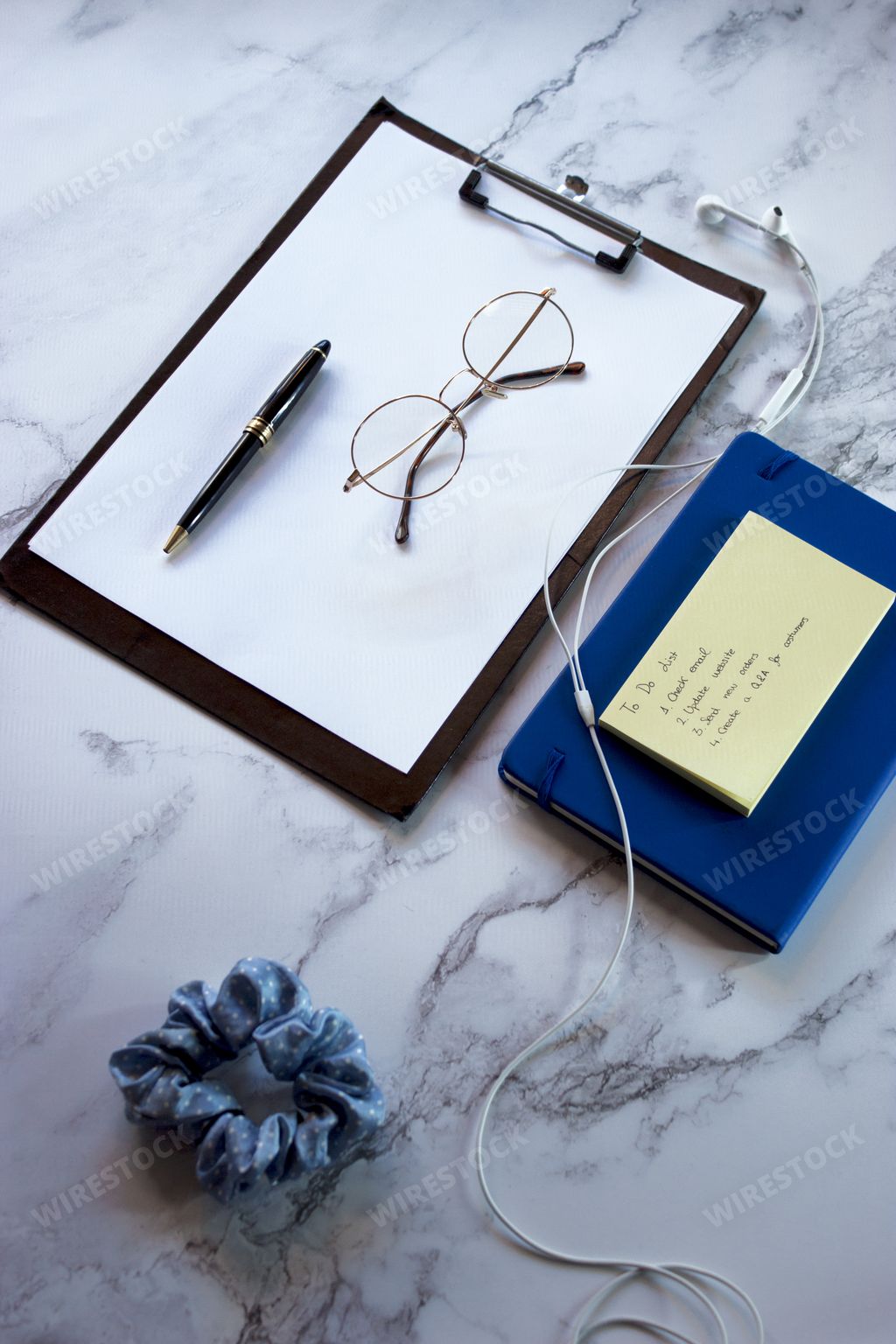 A top view of a notepad with a to-do list with glasses and a pen on a marble surface
