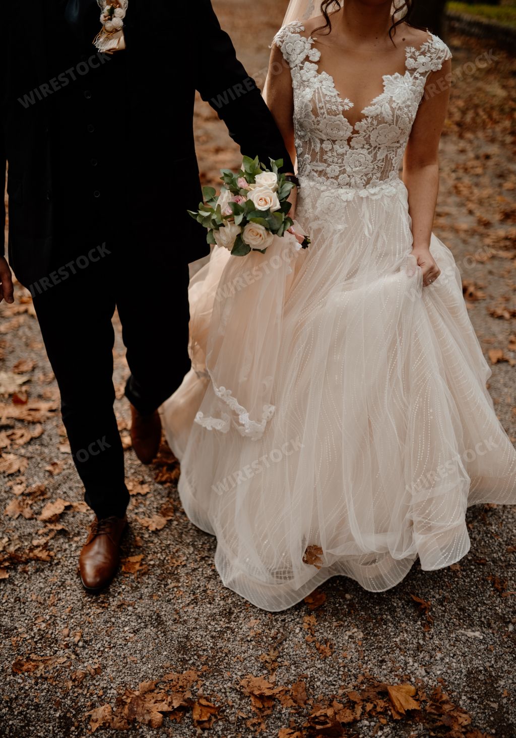 A vertical shot of a groom and a bride walking in a park