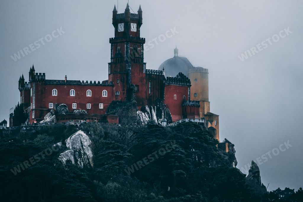 A stunning image of the iconic Pena Palace, situated on the top of Sintra Mountain in Portugal, captured on a misty and moody day