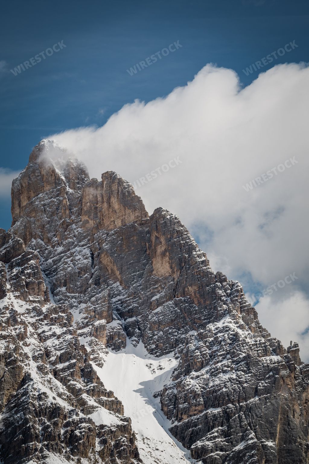 A majestic mountain peak rising above the clouds, blanketed in a layer of pristine white snow
