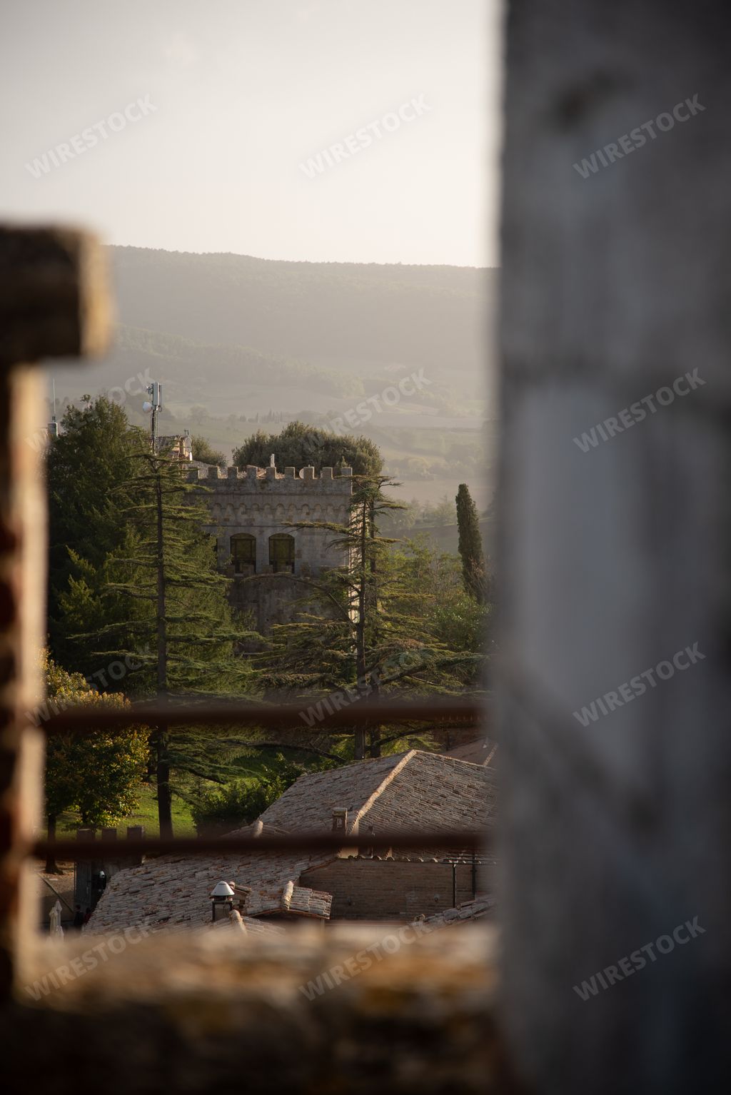 A vertical shot of the old stone building behind the trees. Tuscany, Italy.