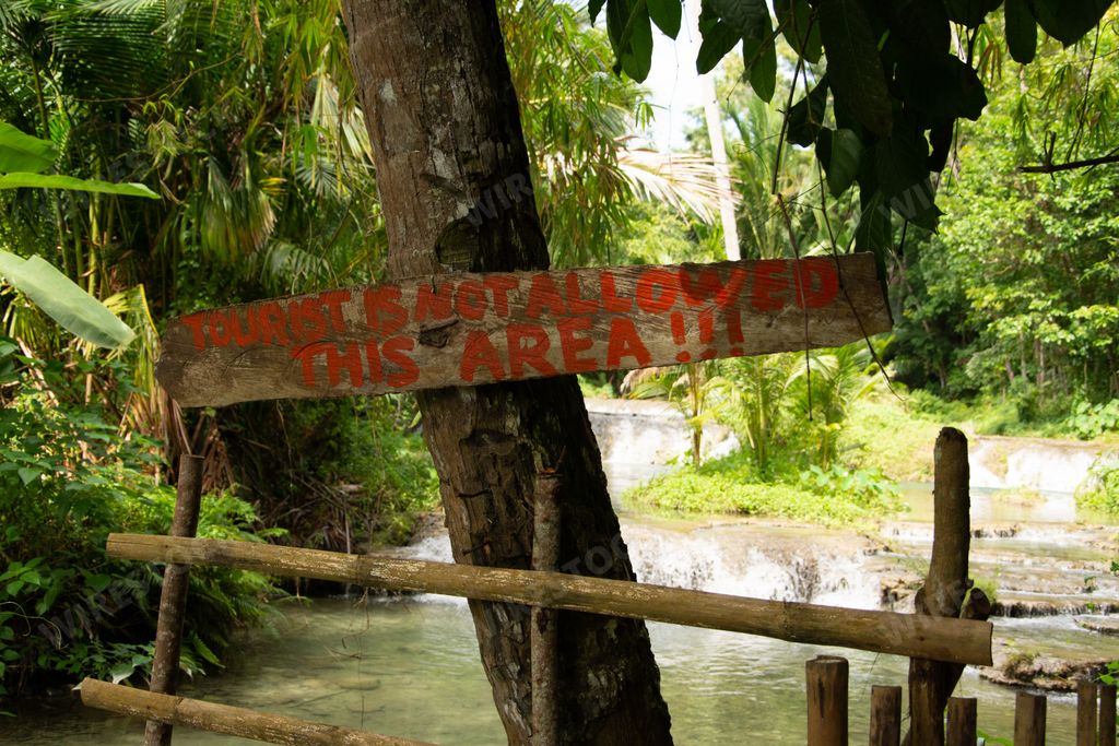 A big wooden warning sign board nailed to a tree banning tourists to enter the area
