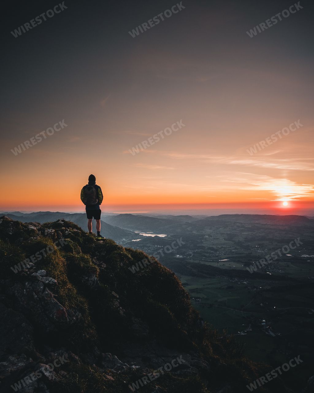 A person standing on a cliff enjoying the beautiful view of the sunset in Switzerland