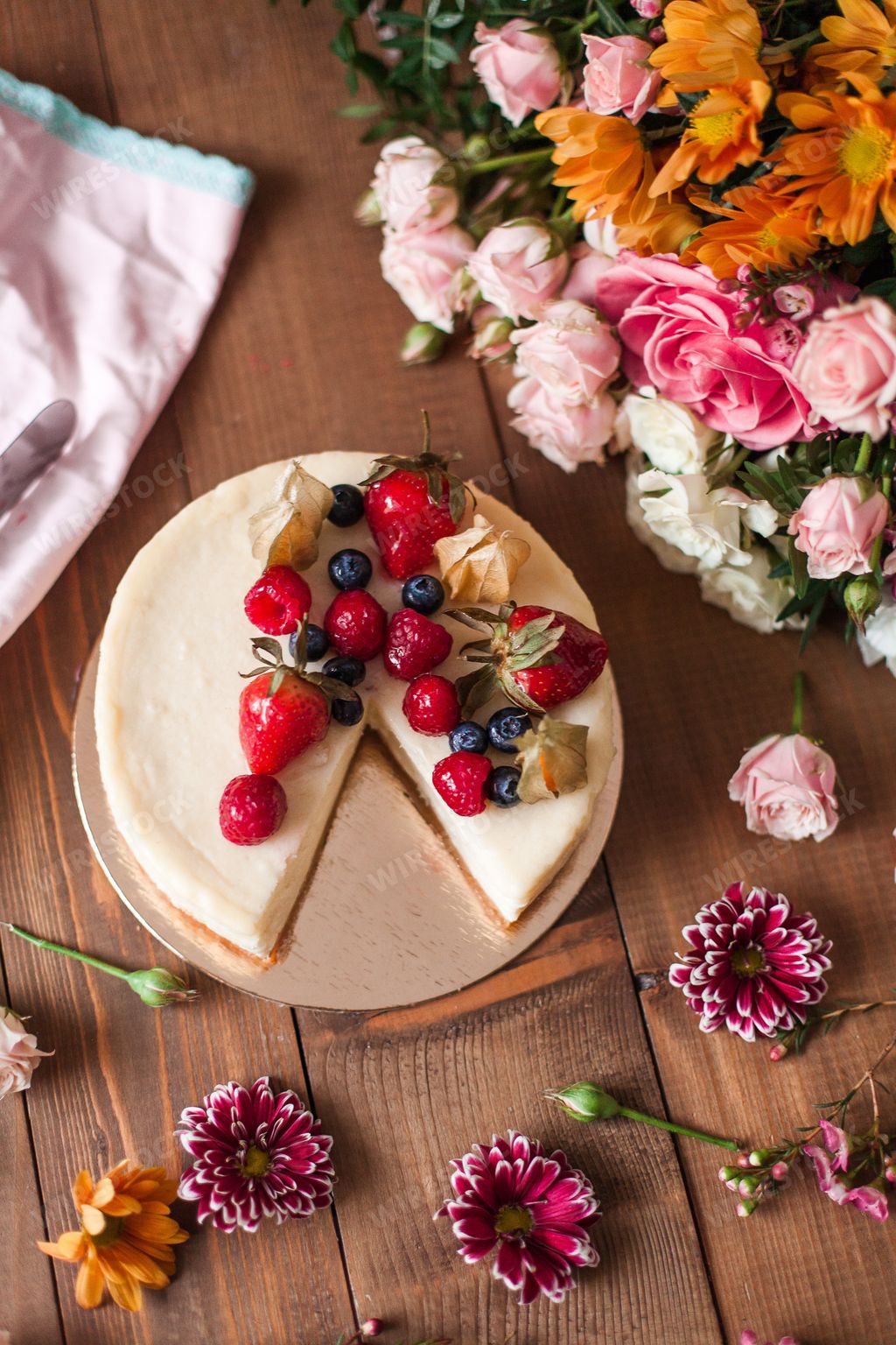 An aesthetic shot of a cheesecake with sweet berries sweet arranged with delicate flowers