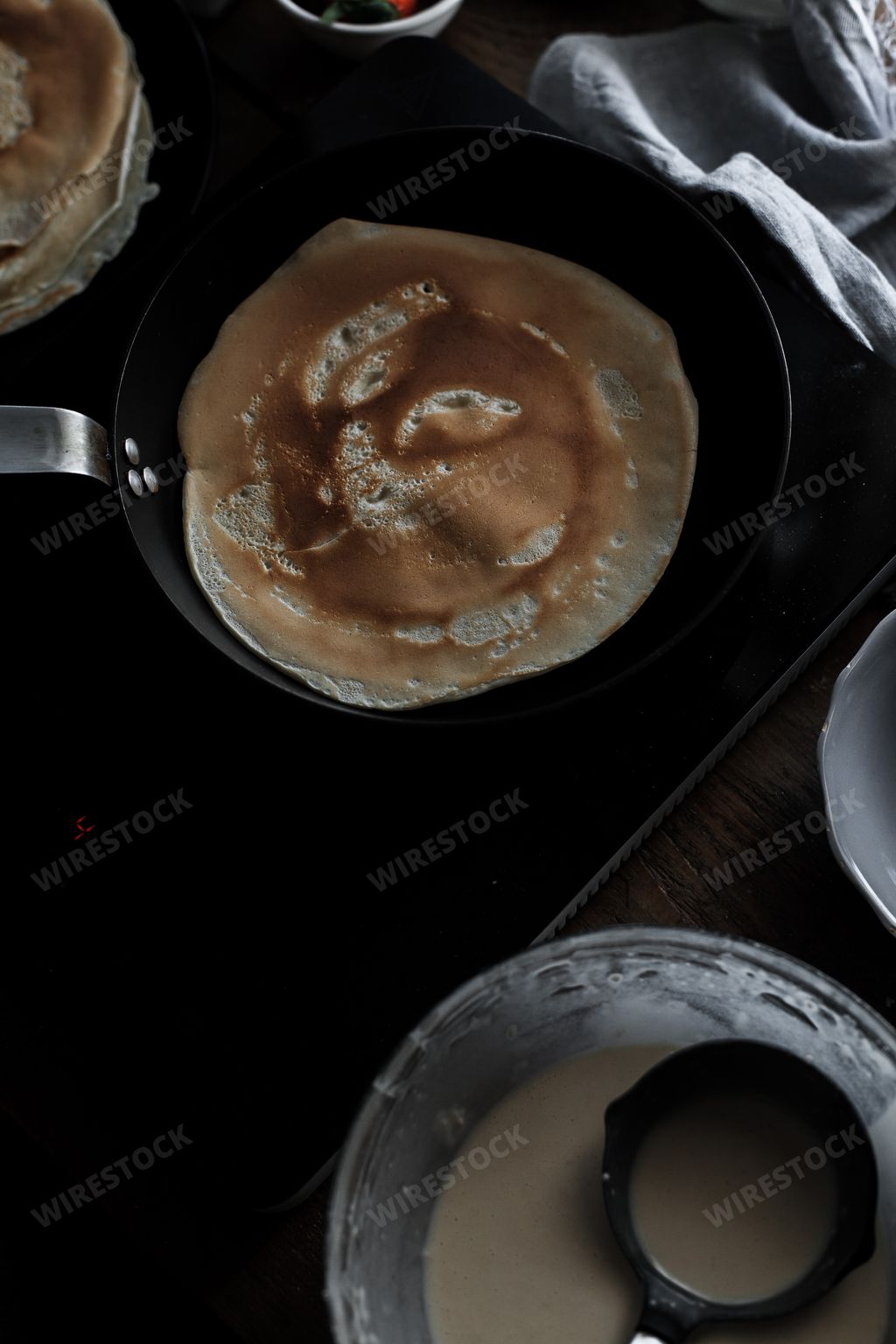 A vertical shot of baking pancakes in a pan in the kitchen