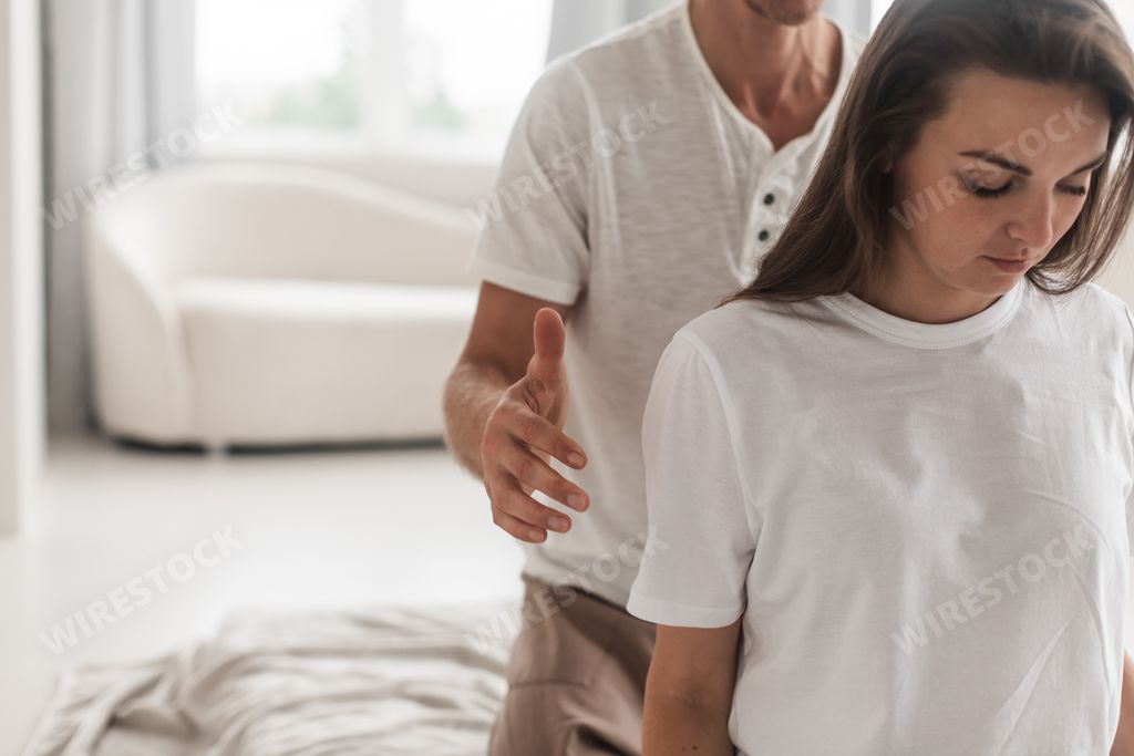 A middle-aged Caucasian masseur and a woman doing Japanese massage exercises on a mat at home