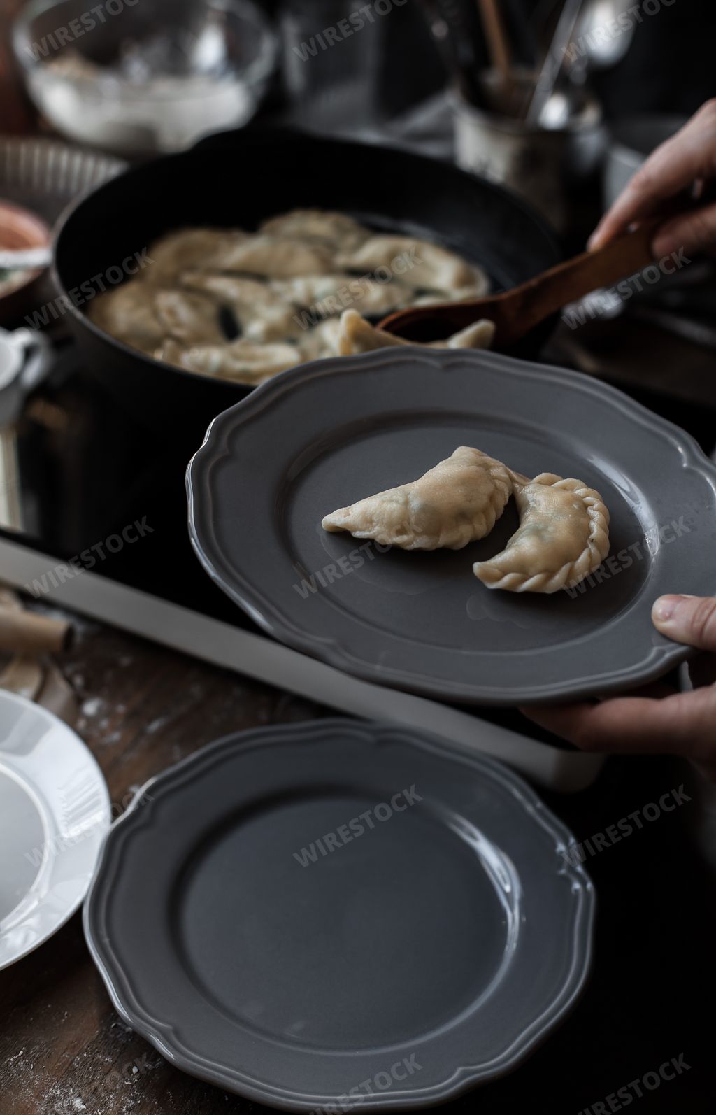 A hand putting dumplings into a plate to serve in the kitchen