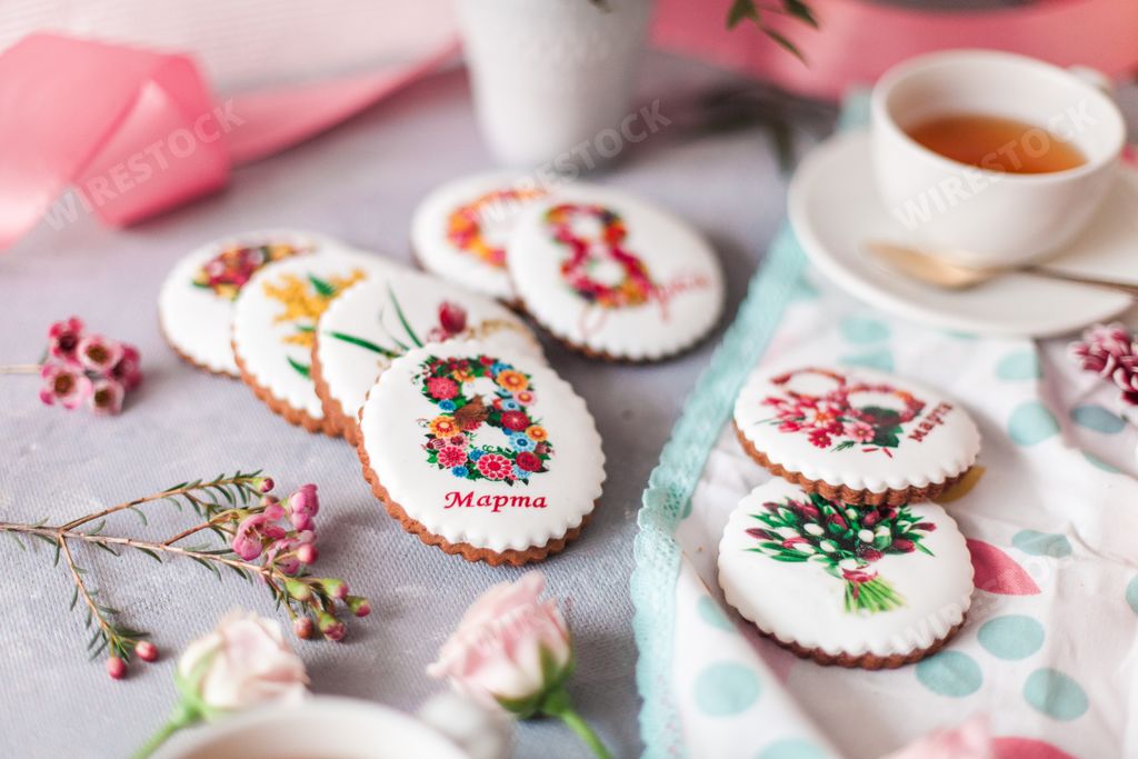 An aesthetic shot of sweet cookies with March 8 wishes served with tea and arranged with flowers