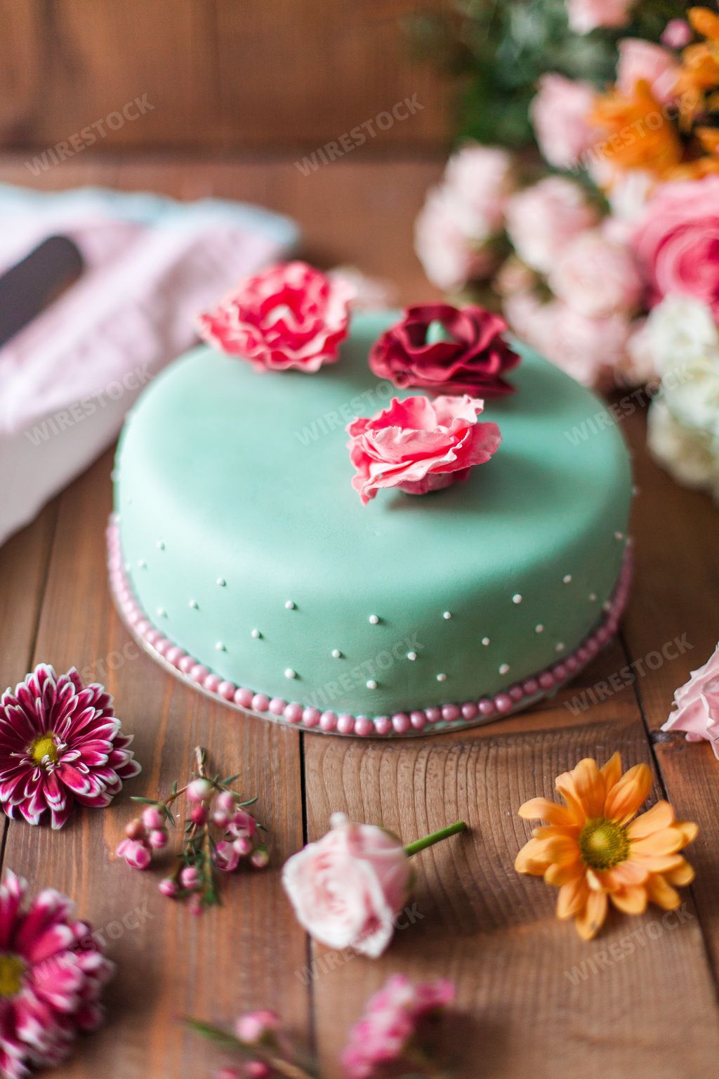 An aesthetic shot of a cake covered by turquoise marzipan arranged with delicate flowers