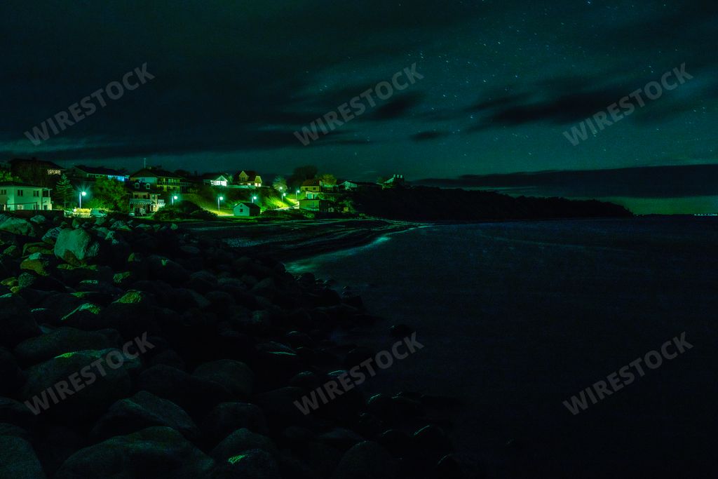 A village on the rocky beach by the sea under the beautiful starry sky