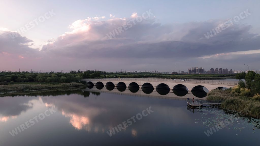 A vibrant wetland park located in Tianjin, China with arch bridge over the lake at sunset