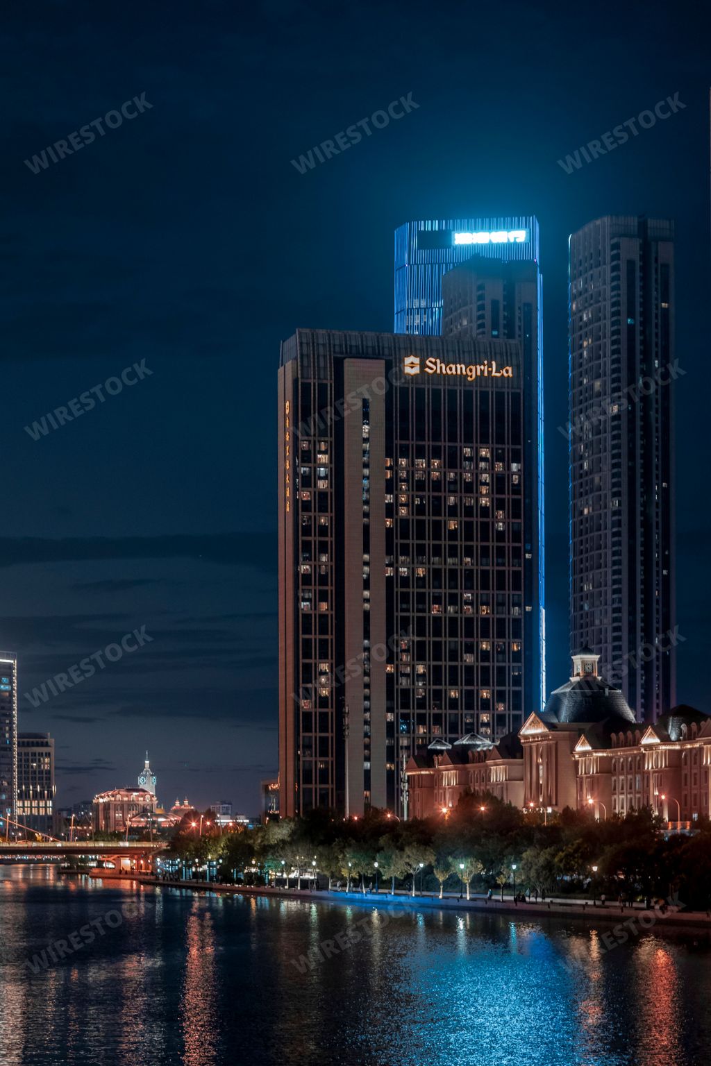 A night scene with illuminated buildings by the Haihe River on dark blue sky background