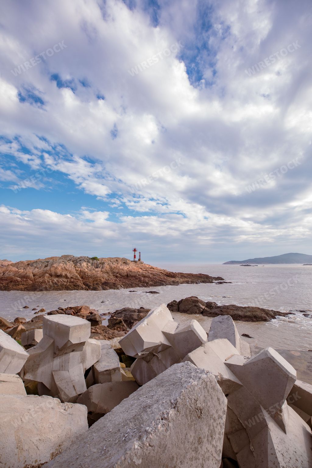 A lighthouse atop a rocky cliff overlooking the vast expanse of the ocean