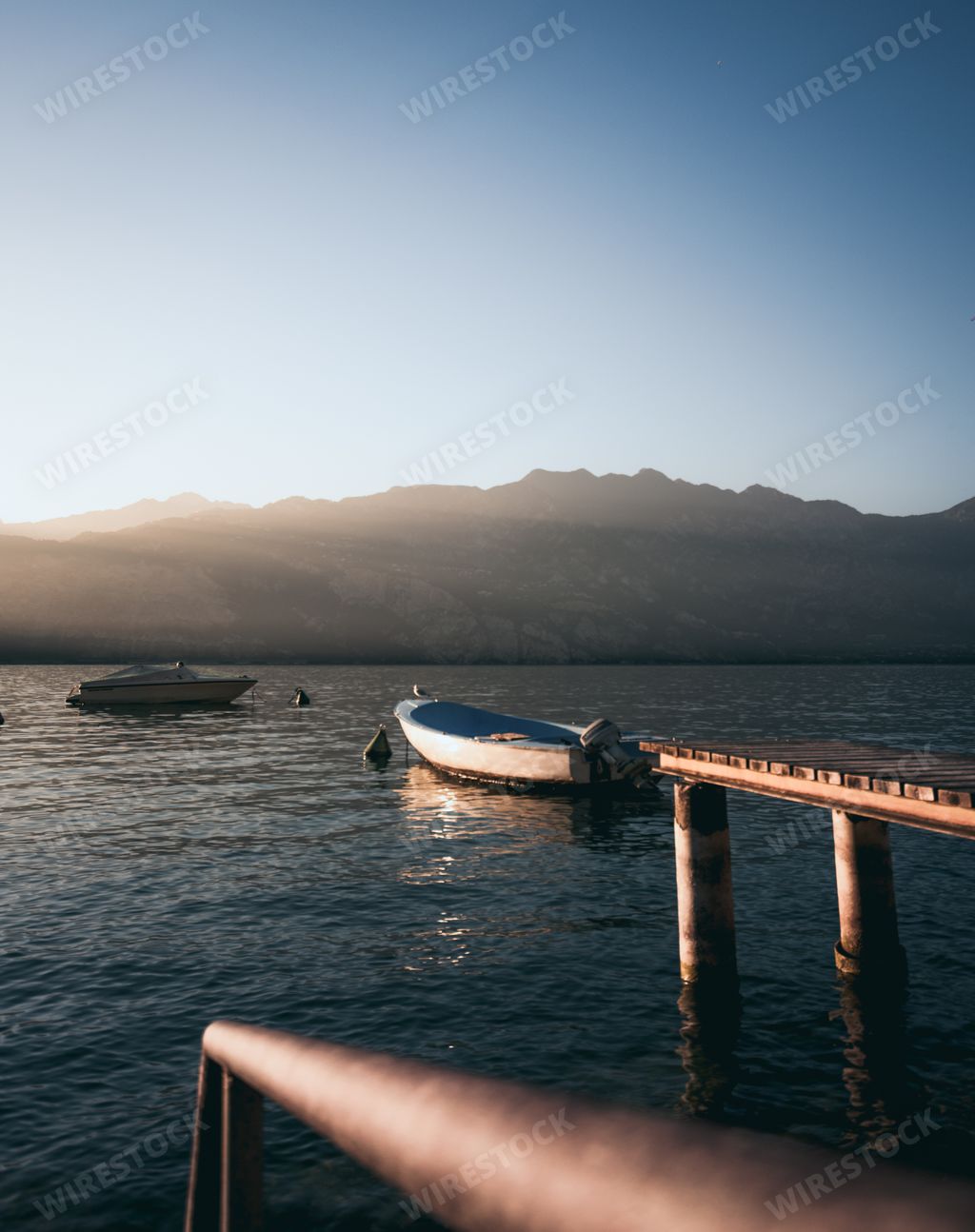 A vertical shot of boats moored on the sea with sunrise background
