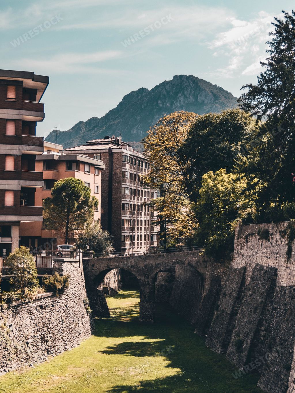 A stone bridge over the grass path in a city