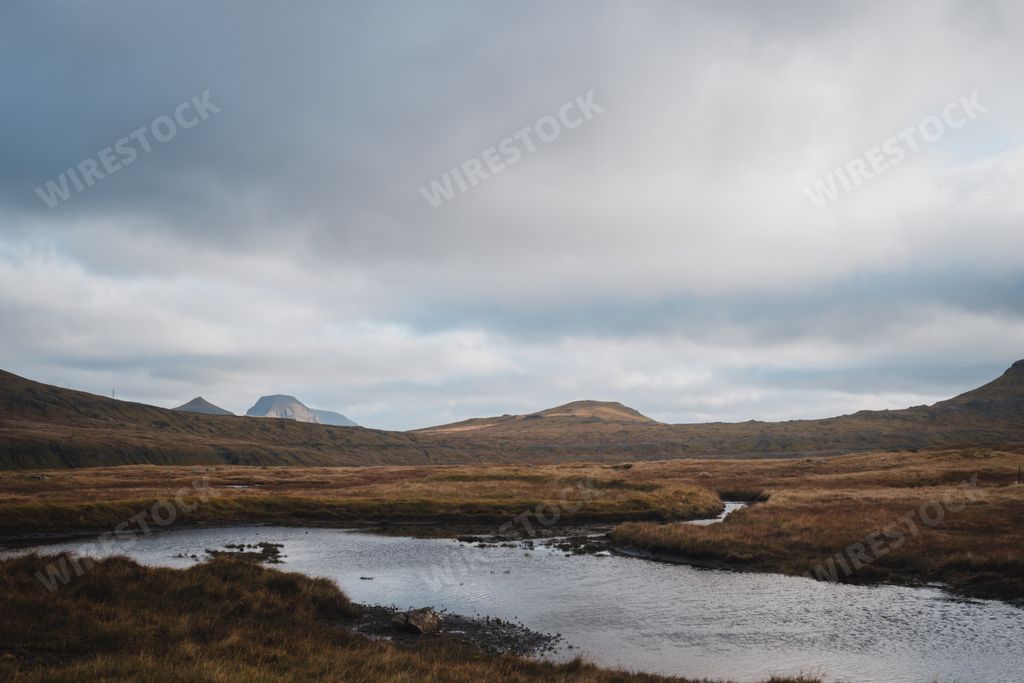 Cloudy sky over mountains and river at Faroe Islands in autumn Denmark. Visit Faroe Islands