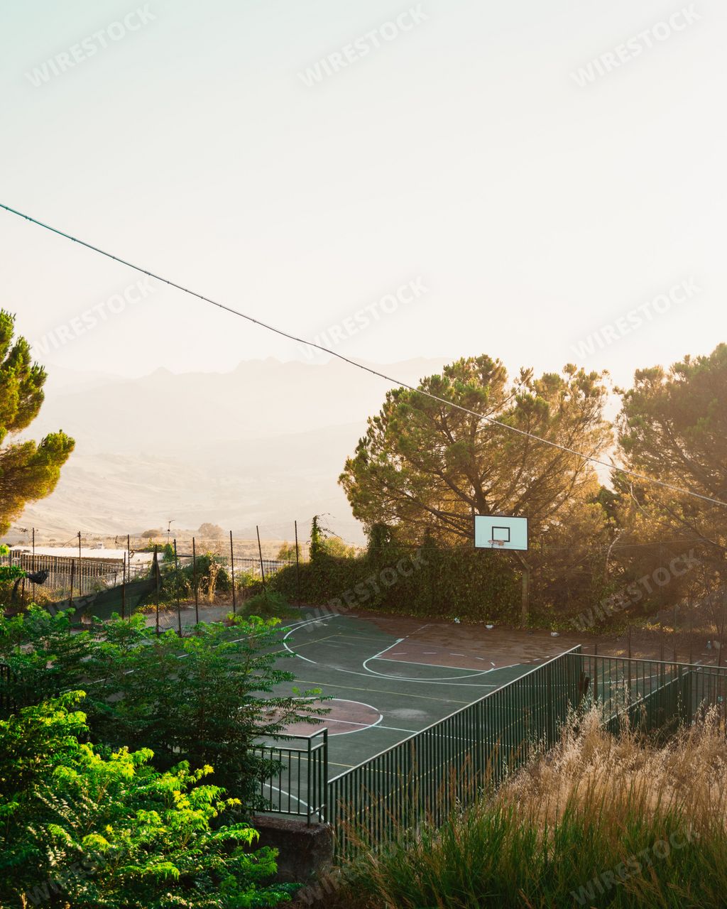 A vertical distant view of a basketball court during sunset