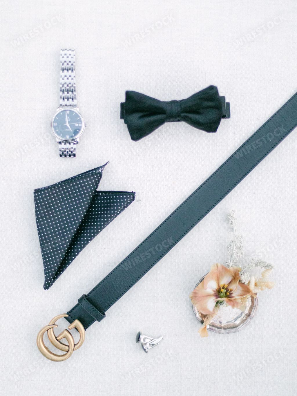 A top view shot of black Leather belt, black bow, watch and pocket Hankerchief on white background