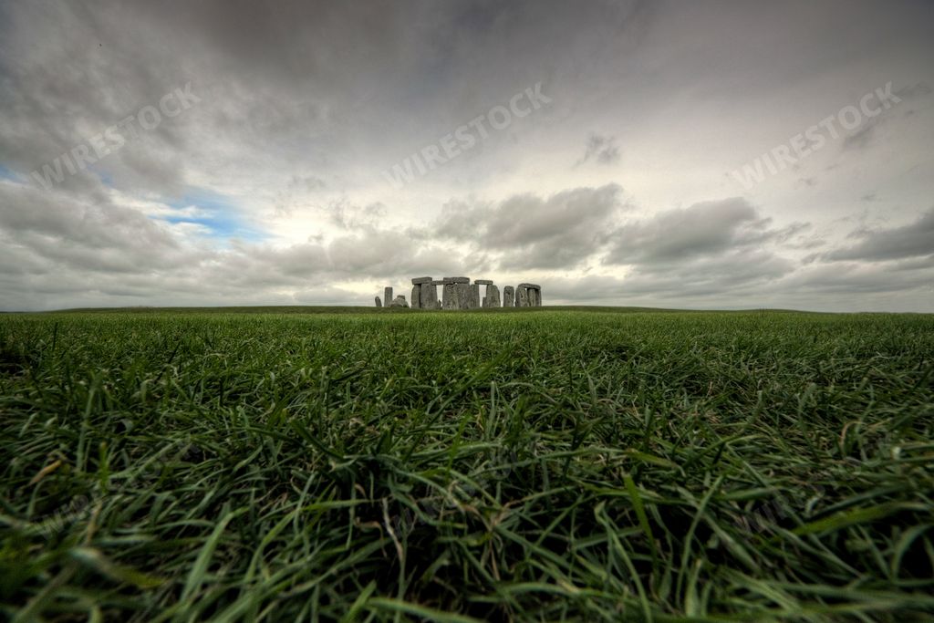 A historic ancient building in the middle of a beautiful green field under the gloomy sky