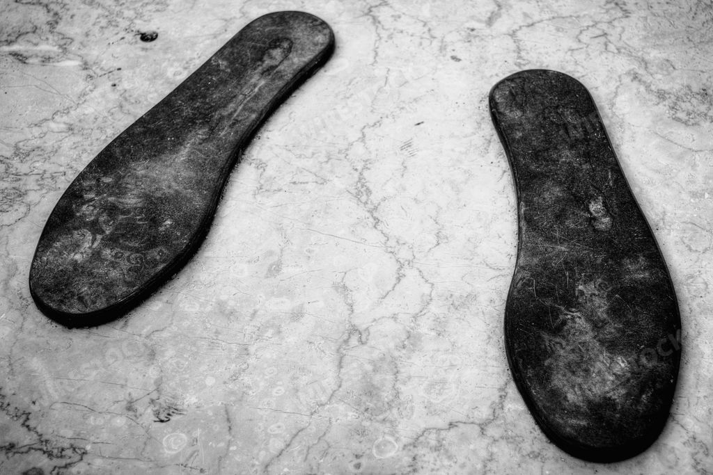 A high angle grayscale shot of shoe  inserts on a marble surface