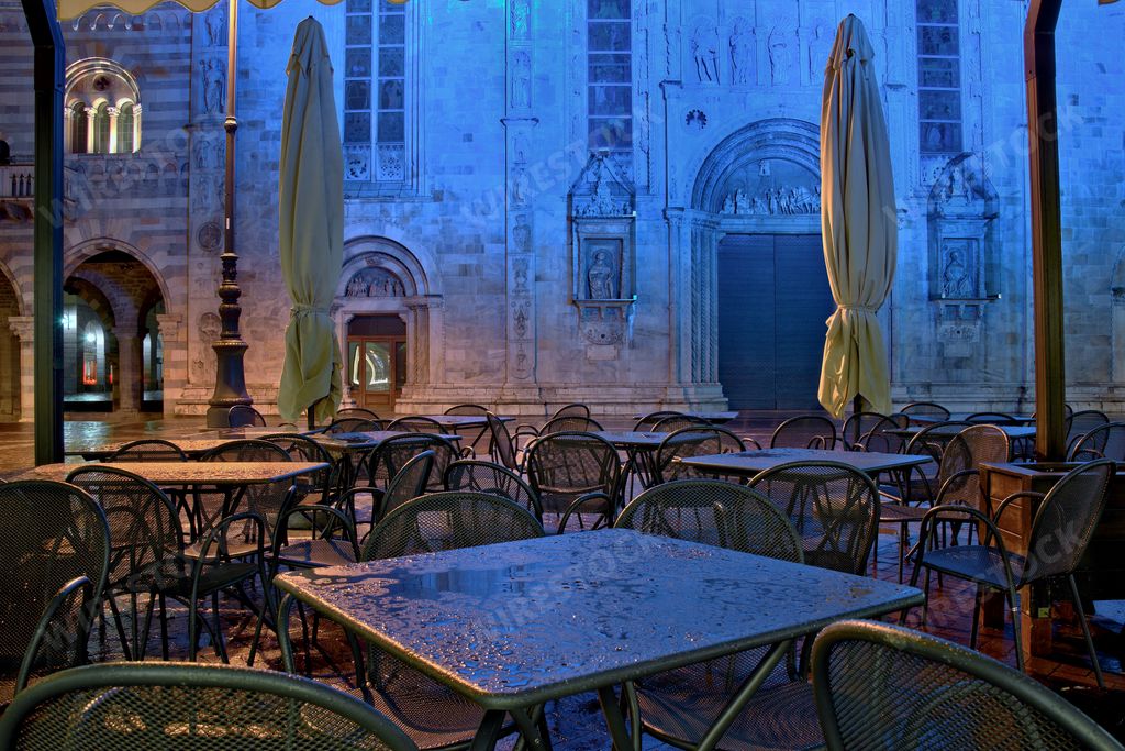 A horizontal shot of an outside cafe with empty chairs and tables in front of an Italian building with nice patterns in Como, Italy
