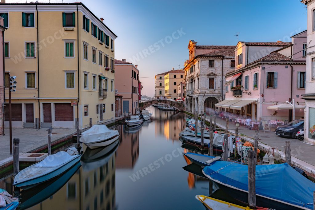The main canal of the city of Chioggia called Little Venice with its boats reflecting the adjacent buildings and shops on the surface