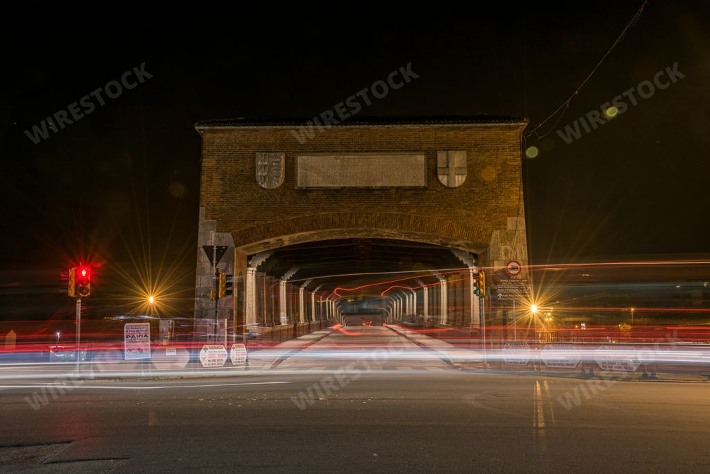 A timelapse shot of car lights on the road near a tunnel at night in Pavia, Italy
