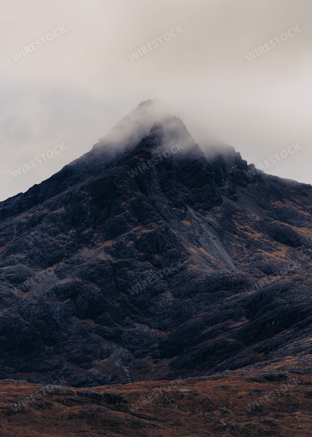 A vertical shot of a mountain covered in a cloud of fog in Scotland, Isle of Skye