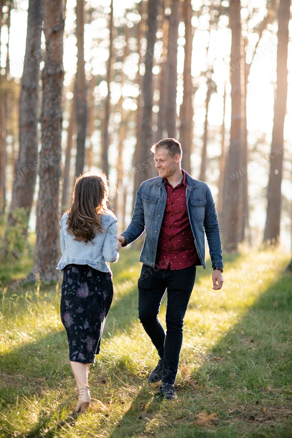 A couple walks hand in hand through the forest, enjoying the natural beauty around them