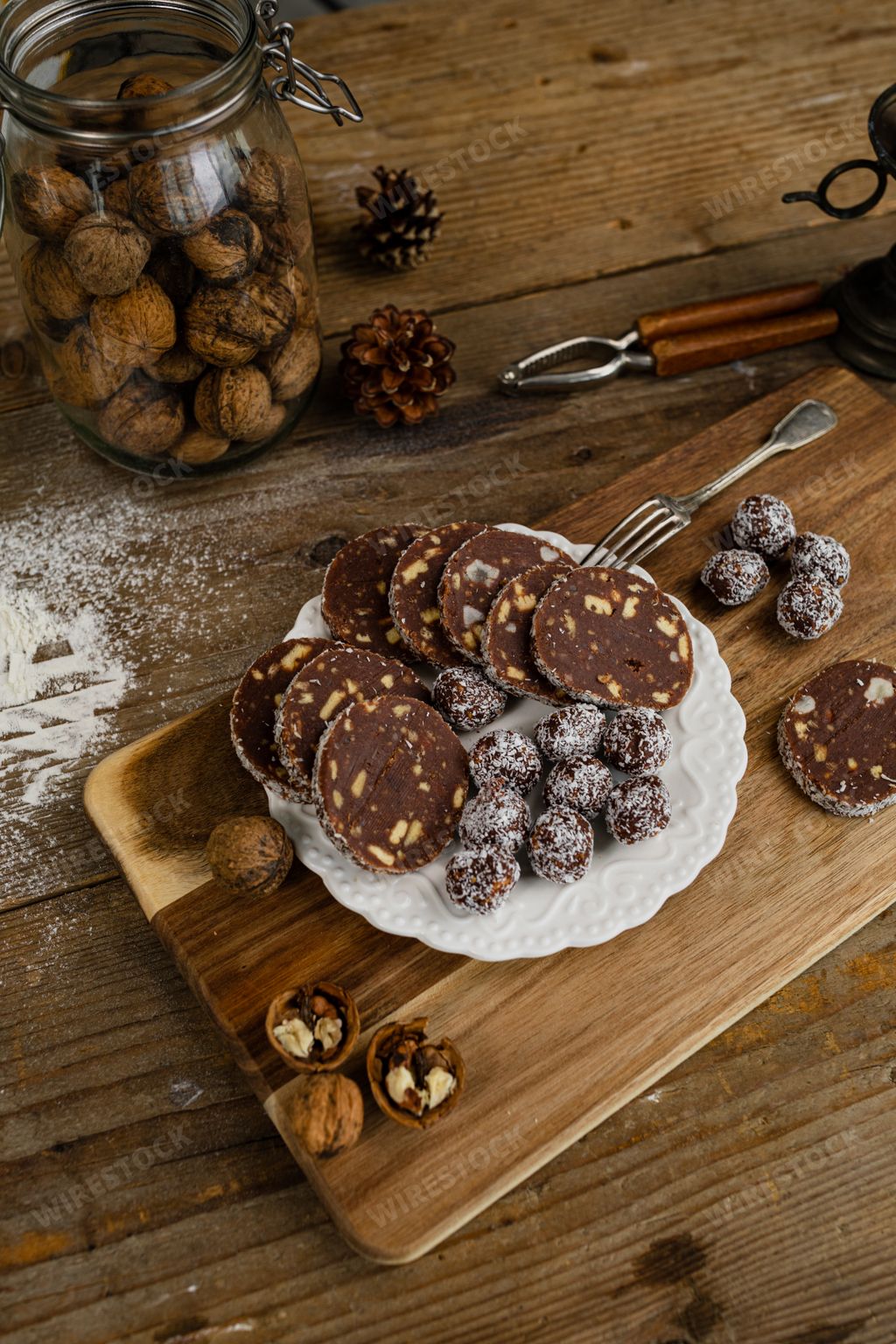 Delicious dried fruit sweets and chocolate sausages on a plate on a wooden board
