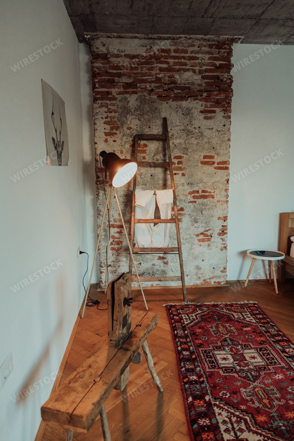 A vertical shot of a loft-stye room with a wooden bench, stair and a colorful carpet