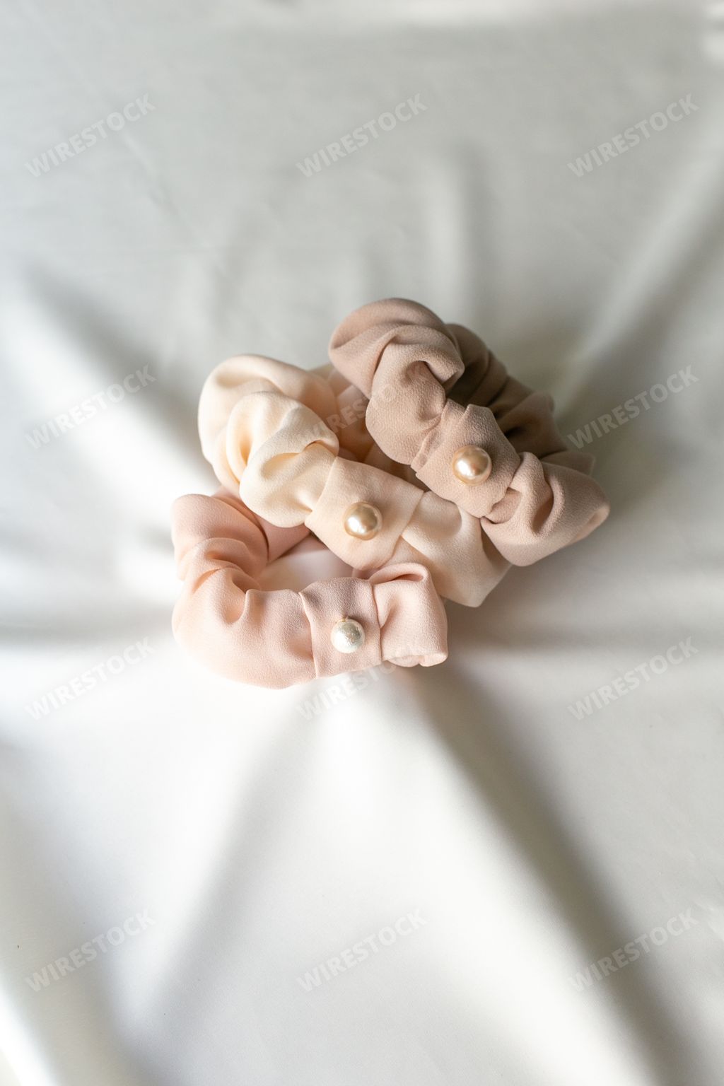 A vertical shot of a fancy hair tie with cute pearls on white background